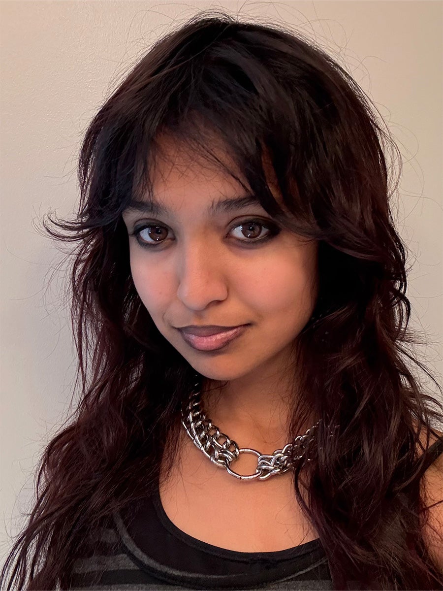 Arianna's headshot is a woman in a black shirt posing in front of a white background.