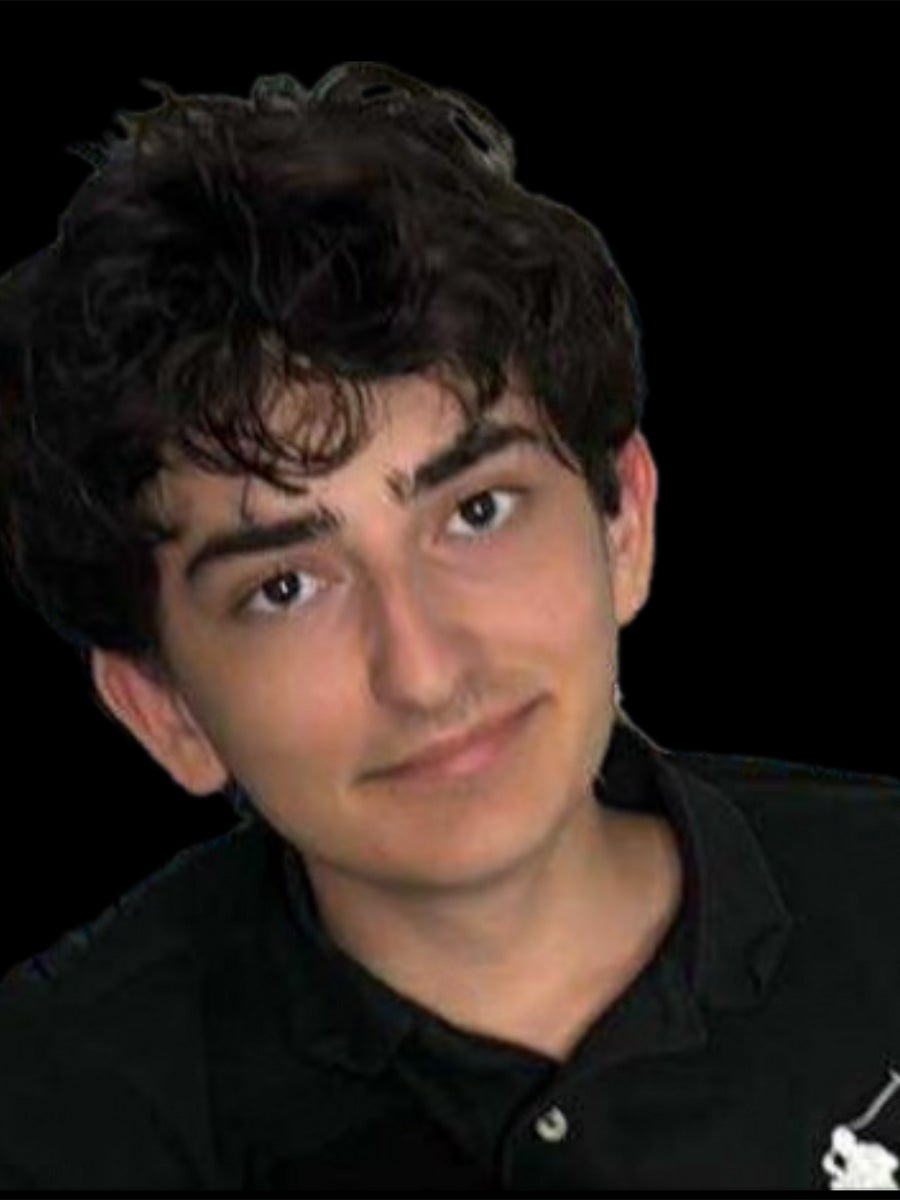 Niko's headshot is a guy with a black shirt and black hair smiling with a black background