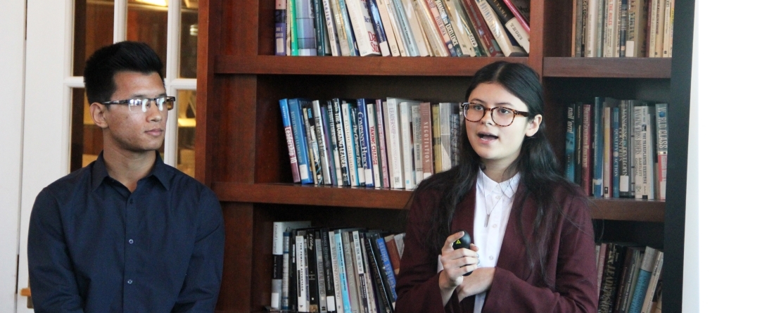 Students presenting in front of bookcase