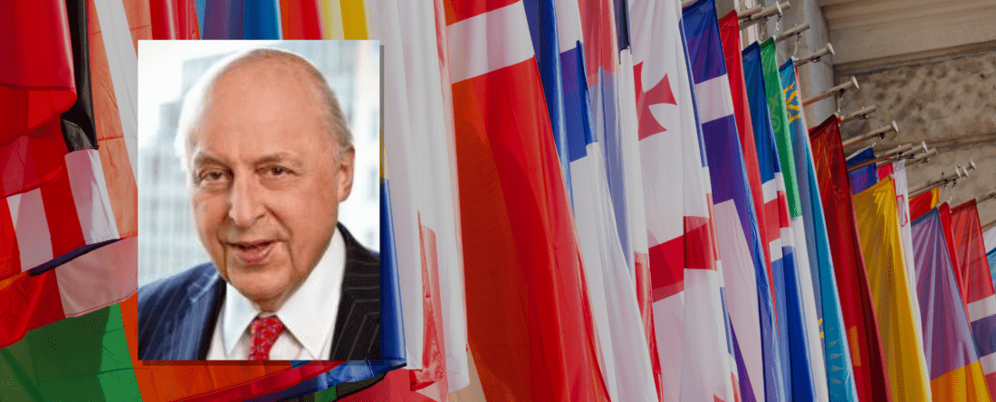 Image of Negroponte in front of wall of flags