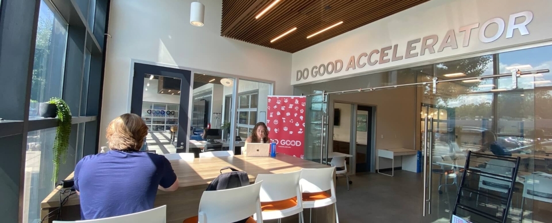 Two students sitting in a well lit room at a table with Do Good Accelerator