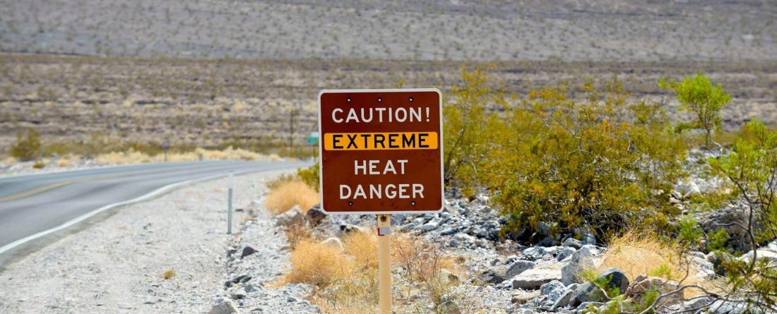 image of sign on side of desert road stating "Caution! Extreme heat danger"