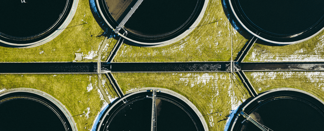 An aerial view of circular vats filled with liquid and infrastructure to handle sewage.