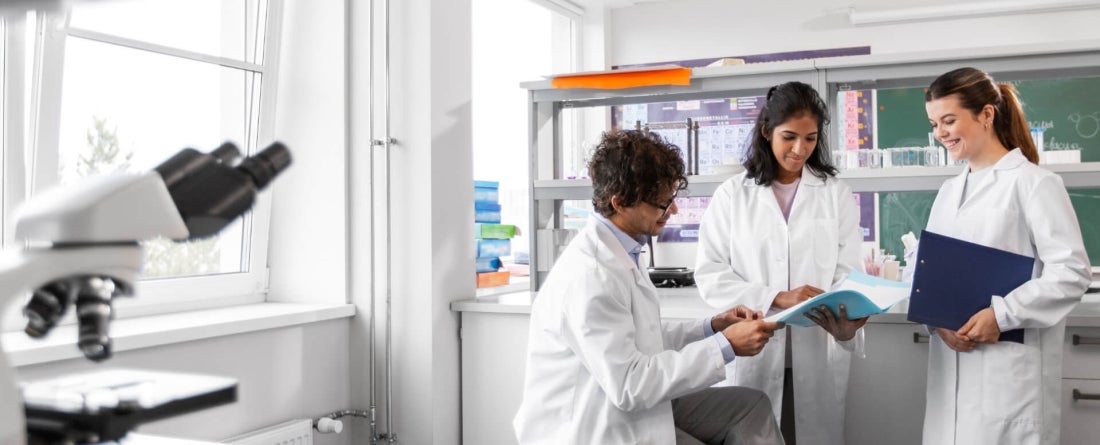 3 people working in a research lab wearing white lab coats